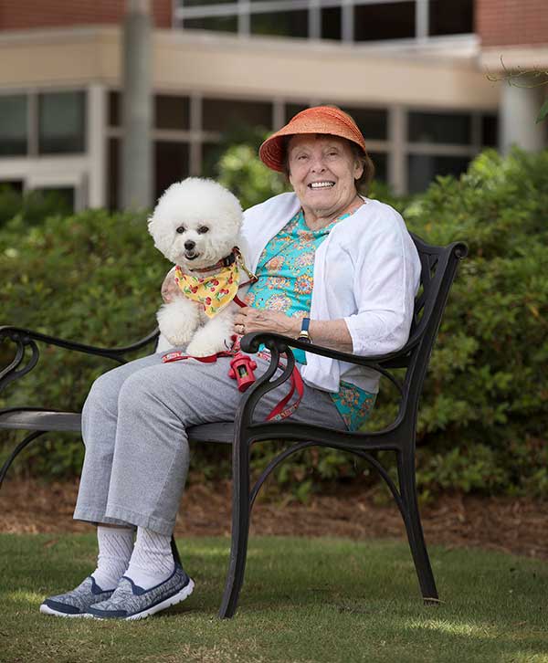 Senior Woman with dog sitting on bench - Lanier Gardens Indpendent Living Options